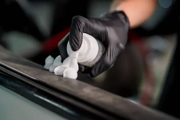 ディテールプロセス中に高級車のドアカードを掃除しながらプラスチック洗浄フォームを適用する洗車労働者のクローズアップ — ストック写真