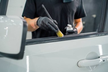 Oto yıkama işçisi, temizlik sırasında lüks bir araba kapısının kartını yıkamak için fırça ve köpük kullanır.