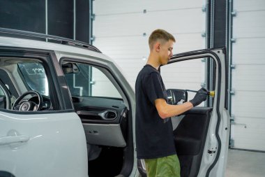 Oto yıkama işçisi, temizlik sırasında lüks bir araba kapısının kartını yıkamak için fırça ve köpük kullanır.