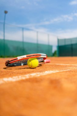 Spor ekipmanları, tenis raketleri ve topları yakın planda yer alan bir spor sahası hobisi yatmaktadır.