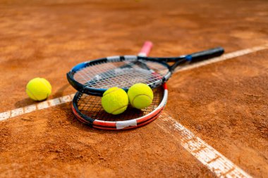 Spor ekipmanları, tenis raketleri ve topları yakın planda yer alan bir spor sahası hobisi yatmaktadır.