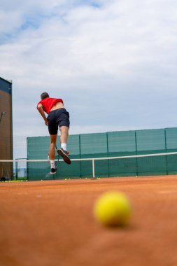 Açık hava tenis kortunun genç profesyonel oyuncu koçu raket tenis topuyla vuruşlar yapıyor.