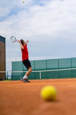 Açık hava tenis kortunun genç profesyonel oyuncu koçu raket tenis topuyla vuruşlar yapıyor.