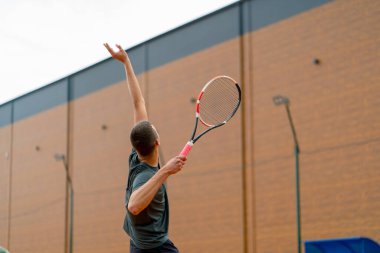 Açık hava tenis kortunun genç profesyonel oyuncu koçu raket tenis topuyla vuruşlar yapıyor.