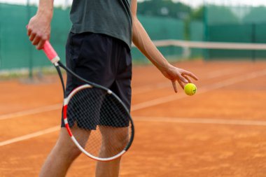 Açık hava tenis kortunun genç profesyonel oyuncu koçu raket tenis topuyla vuruşlar yapıyor.