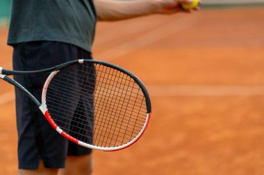 Açık hava tenis kortunun genç profesyonel oyuncu koçu raket tenis topuyla vuruşlar yapıyor.