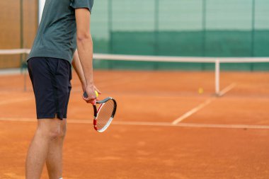 Açık hava tenis kortunun genç profesyonel oyuncu koçu raket tenis topuyla vuruşlar yapıyor.