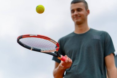 Genç tenis oyuncusu antrenörü tenis kortunda raketle topa vuruyor ve spor yaşam tarzı yarışmasına hazırlanıyor.