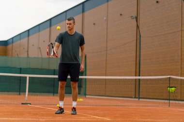 Genç tenisçi koç tenis kortunda raketle topa vuruyor ve spor yaşam tarzı yarışmasına hazırlanıyor.