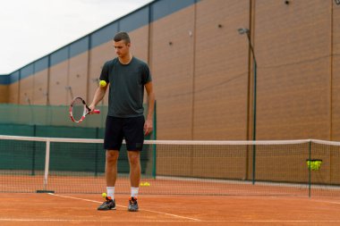 Genç tenisçi koç tenis kortunda raketle topa vuruyor ve spor yaşam tarzı yarışmasına hazırlanıyor.