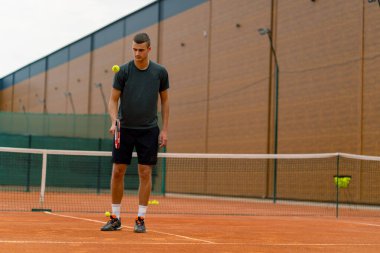 Genç tenisçi koç tenis kortunda raketle topa vuruyor ve spor yaşam tarzı yarışmasına hazırlanıyor.
