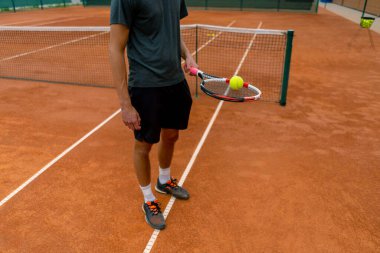 Genç tenis oyuncusu antrenörü tenis kortunda raketle topa vuruyor ve spor yaşam tarzı yarışmasına hazırlanıyor.