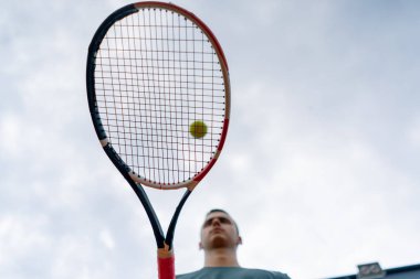 Genç tenis oyuncusu antrenörü tenis kortunda raketle topa vuruyor ve spor yaşam tarzı yarışmasına hazırlanıyor.