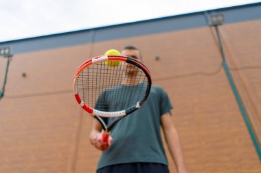 Genç tenis oyuncusu antrenörü tenis kortunda raketle topa vuruyor ve spor yaşam tarzı yarışmasına hazırlanıyor.