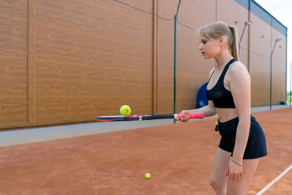 若い少女初心者テニスプレーヤーは 裁判所の列車のラケットでボールをヒットし スポーツ趣味にヒットすることを学ぶ — ストック写真
