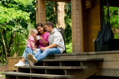 Bir erkek ve bir kadının genç bir ailesi ormandaki ahşap evlerinin satın alınmasıyla seviniyor.