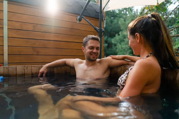 A man and woman in love in swimming costumes relaxing in an outdoor pool at a spa in the woods
