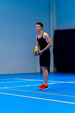 Genç şişirilmiş sporcu voleybol maçı ya da maç sırasında topa servis yapmaya hazırlanıyor.