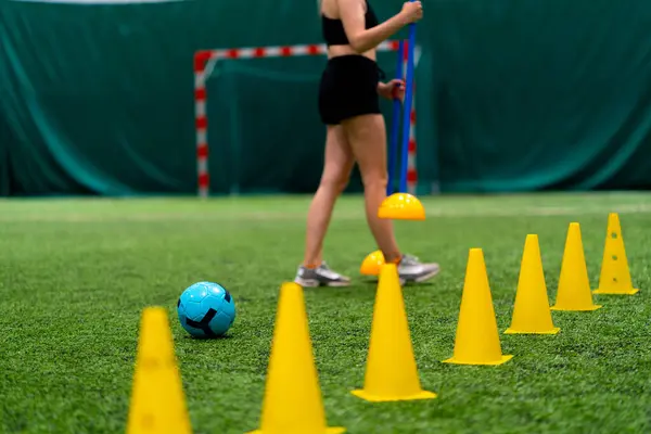 若い少女のサッカー選手は試合のための訓練の準備の前に閉鎖したサッカー場のスポーツ装置の破片を表示します — ストック写真
