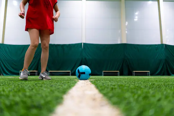 サッカー選手の足がペナルティやゴールのためにボールを蹴るか サッカーの試合中に緑の合成草にボールを渡す — ストック写真