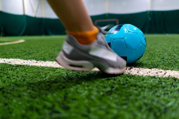 close-up of a soccer player\'s foot kicking the ball for a penalty or a goal or passing a ball on green synthetic grass during football game
