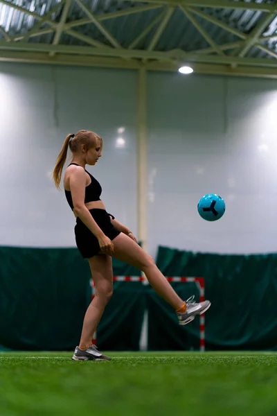 若い女の子は 彼女のスポーツスキルを向上させる空気でそれを投げるボールを蹴るサッカー場でトレーニングしています — ストック写真