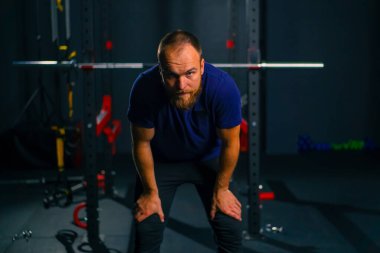 Eğitimden sonra spor salonunda yorgun bir sporcunun portresi alnından terini eliyle siler.