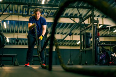 Konsantre kadın atlet spor konsepti spor kaslarını eğitmek için halatla egzersiz yapıyor.