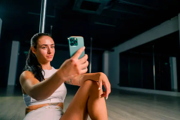 portrait of a young beautiful sexy girl after a dance class on a pole holding a phone in her hands taking photo of herself active lifestyle hobby