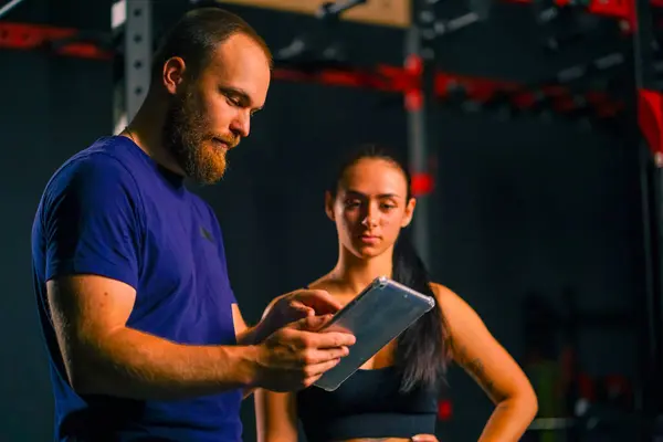 Male Trainer Holds Tablet His Hands Shows Training Schedule Female — Stock Photo, Image