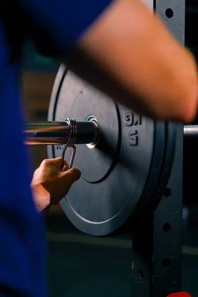 男子田径教练给健身房的杠铃增加了重量 从而增加了健美运动员的身体负荷 — 图库照片