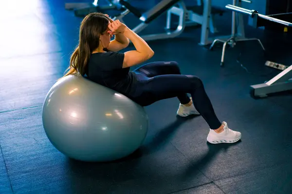 concentrated fitness woman trainer doing abs exercises on inflatable ball gym hard sport motivation