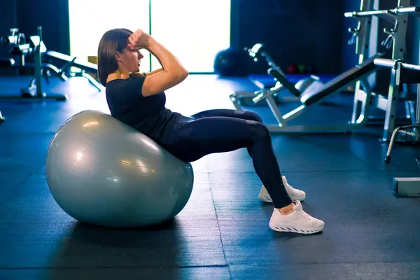 concentrated fitness woman trainer doing abs exercises on inflatable ball gym hard sport motivation