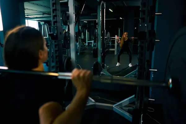 濃縮フィットネス女性は バーベルジムトレーニング筋肉グループのバックビューで重い肩プレスエクササイズを行います — ストック写真