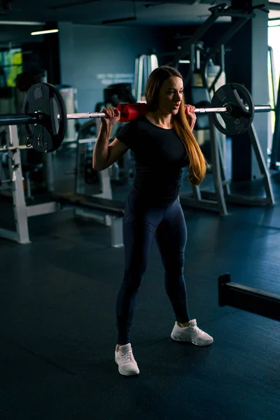 在体操训练肌群中 一个全神贯注的健康女人用杠铃做一个沉重的肩压运动的肖像 — 图库照片