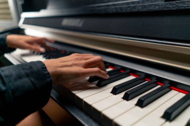 Beyaz ve siyah piyano tuşlarında lirik bir melodi çalan gümüş yüzüklü bir kadının parmaklarının yakın çekimi