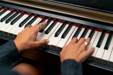 Piyano tuşlarında güzel bir lirik melodi çalan gümüş yüzüklü bir kadının ellerinin yakın çekimi.