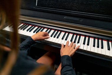 Piyano tuşlarında güzel bir lirik melodi çalan gümüş yüzüklü bir kadının ellerinin yakın çekimi.