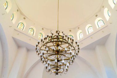 Müslüman camiinin beyaz tavanında güzel bir altın avizesi asılı duruyor.