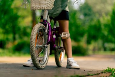 Çocukken parkta bisiklete binen çocuk bacaklarının pedallara yakın çekimi.