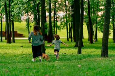 Arkaya bakan aile kızı ve kırmızı köpeğiyle parkta yürüyen genç anne mutlu çocukluk aşk hayvanları.