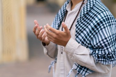 Müslüman bir caminin avlusunda dua eden bir Arap 'ın ellerini ve tespihini yakından çek.