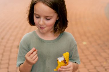 Şehir parkında küçük şekerlemeler yiyen güzel bir kız portresi Mutlu tasasız bir çocukluk