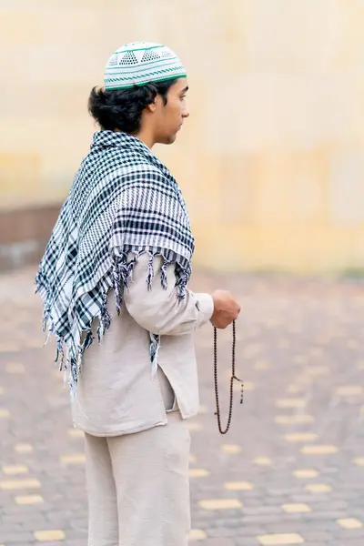 stock image A guy of Arab appearance in national clothes with a rosary in his hand prays and worships Allah in the mosque