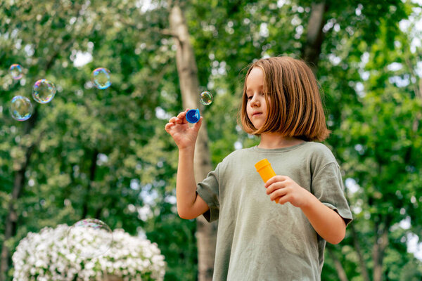 portrait beautiful cute little girl blowing soap bubble in city park happy carefree childhood