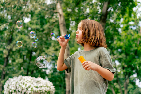portrait beautiful cute little girl blowing soap bubble in city park happy carefree childhood