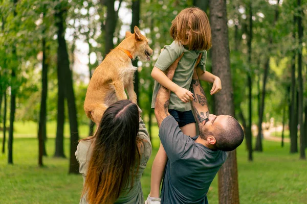 happy young family in park with dog dad holding daughter in arms concept trust care and family values