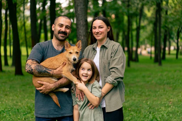 portrait of happy young family in park with dog dad mom daughter resting concept trust care and family values