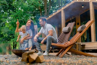 Şirin, genç bir aile babası, anne ve kızı ormanda bir ateşin başında oturmuş, kır evlerinin yanında şekerleme kızartıyorlar.