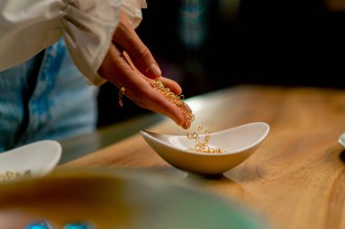 Bir kolye için güzel boncuklar saçan yakın plan kadın elleri ya da güzel sanatlar mücevheri üreten küpeler.